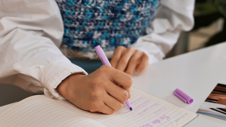 Manos escribiendo notas en cuaderno con marcador violeta - Violeta Costilla Marketing Social